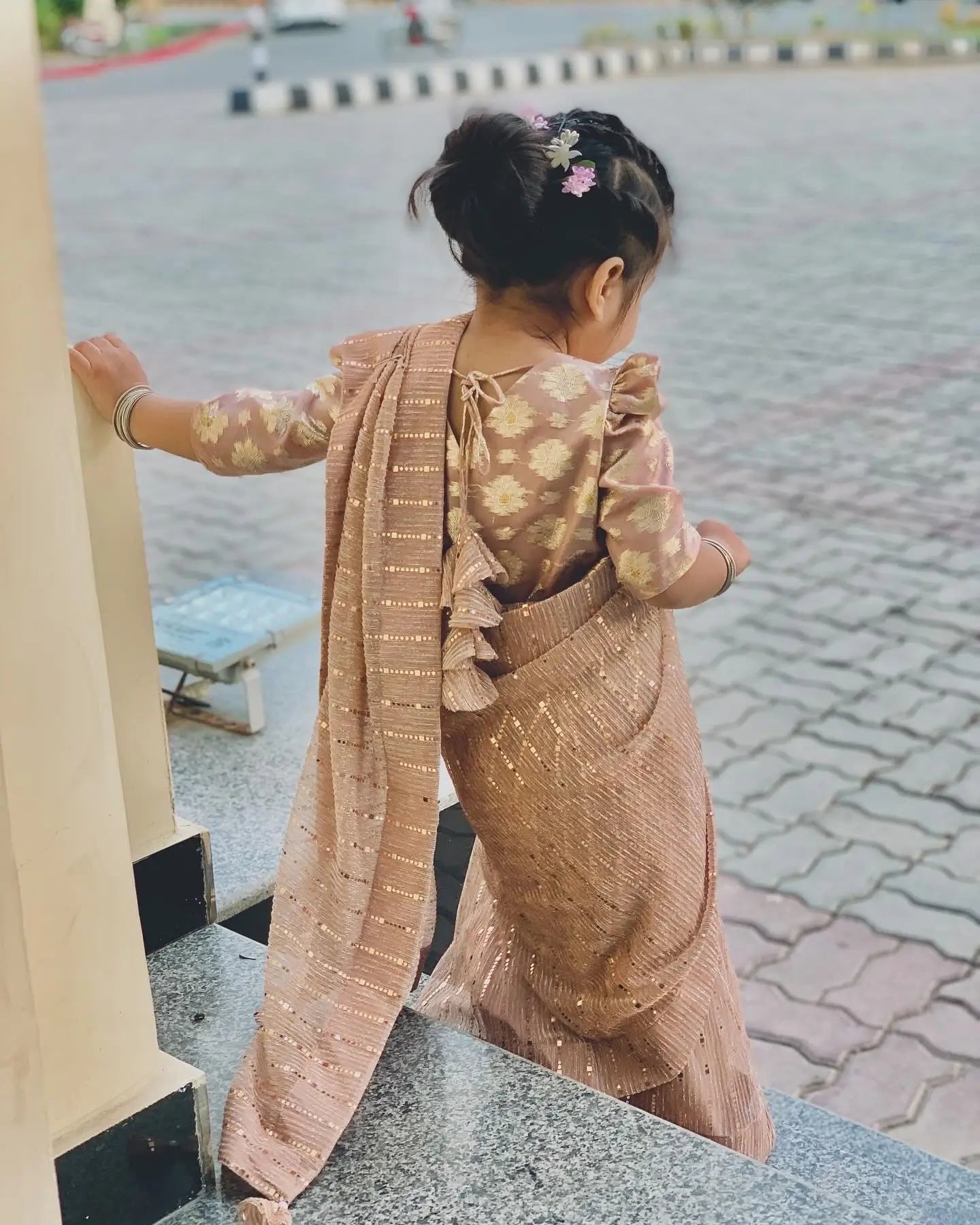 Child in a traditional outfit standing on a street corner